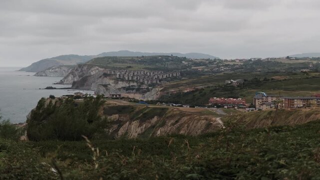 Overcast view of the scenic Basque Country coastline, showing cliffs, the Cantabrian Sea, and residential buildings