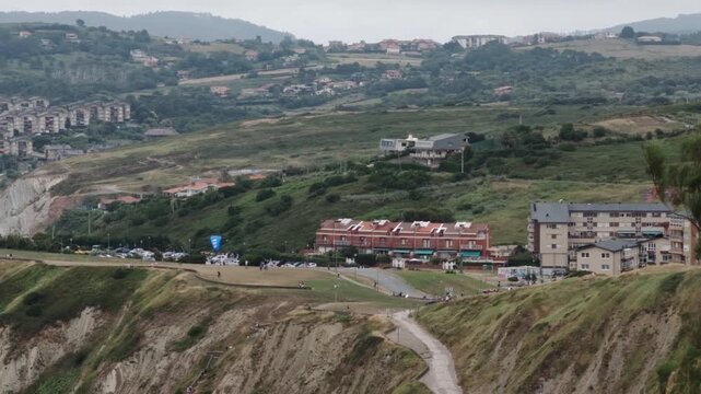 Paragliders launching from coastal cliffs in Sopelana, Basque Country, with residential buildings and beaches below