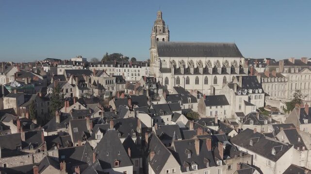 An aerial view shows the tall spire and roofline of Blois Cathedral rising above the surrounding town rooftops.