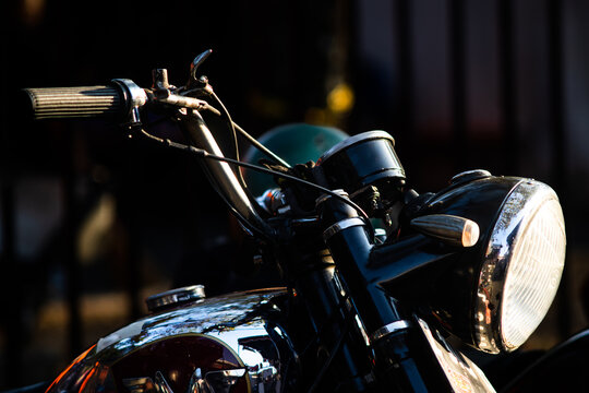 Classic antique motorcycle with polished chrome round headlight handlebar and fuel tank close up