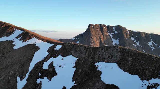Ben Nevis aerial with Carn Mor Dearg, Scottish Highlands, aerial (drone), snow and blue skies, flying over ridge to reveal north face cliffs of Ben Nevis