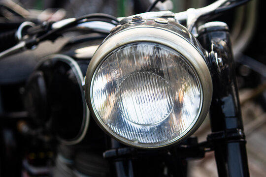 Close up front view of classic black motorcycle glass headlight lens with chrome bezel