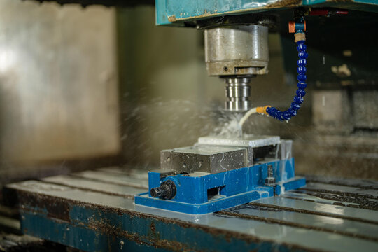 Traditional machine shop equipment in a traditional metalwork factory, close detail of the milling spindle and collet with the blue segmented coolant, heritage machinery of a family run