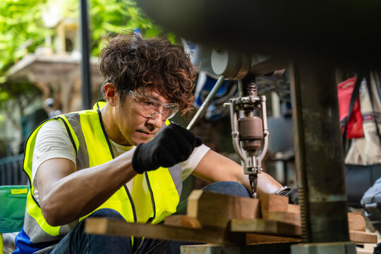 Middle aged Thai craftsman in his vintage metal workshop, dad's fist lower near the chuck, head slightly more upright than adjacent, craftsmanship and dedication behind a small family