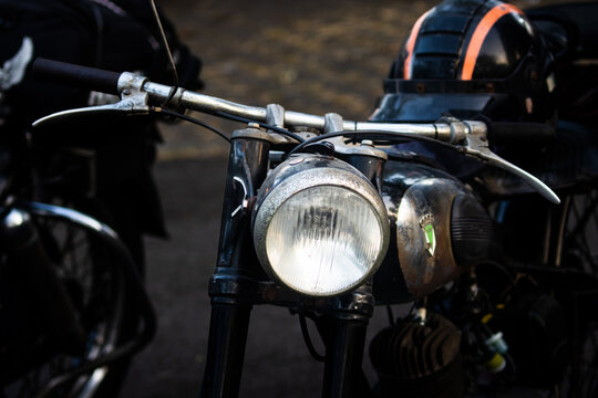 Front perspective of vintage motorcycle with round headlight and metallic fuel tank