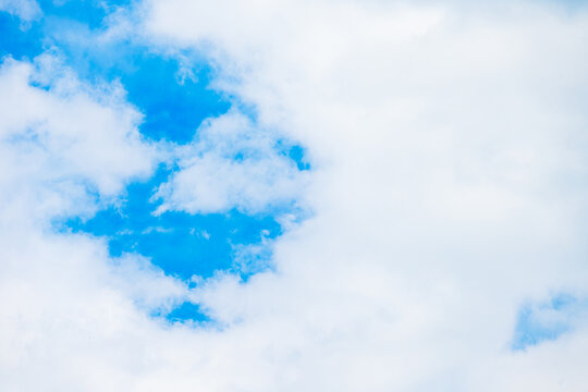 Soft, white fluffy clouds drifting across a vibrant blue sky, creating a peaceful and airy atmosphere. High resolution, ideal for serene backgrounds