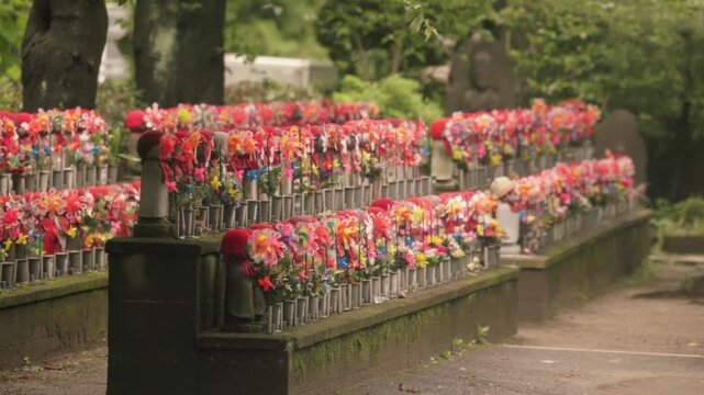 Rows Of Jizo Stone Statues Decorated With Colorful Flowers, Red Hats, And Pinwheels At Zojoji Temple In Tokyo, Japan. Static Shot