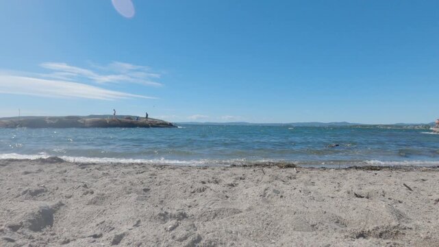 Low angle view of sandy shore and blue sea water with small breaking waves