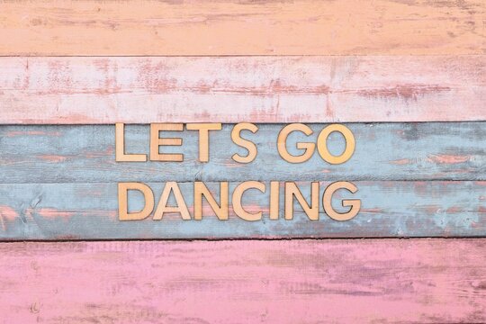 lets go dancing write on wooden background 