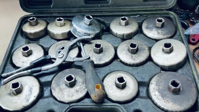 Professional oil filter wrench cup socket set inside a tool case with adjustable pliers. Industrial tools for car mechanics, auto repair shop service and vehicle maintenance equipment.
