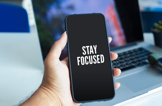 Hand Holding Smartphone Displaying Stay Focused Text