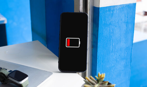 Smartphone Displaying Low Battery Icon Standing on Desk