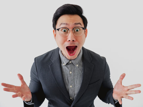 Surprised Asian businessman with wide eyes and open mouth expressing shock or amazement.