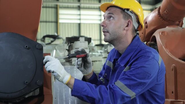 Robotics male engineering collaboratively checked installed electronic components  robot's structure verifying specifications tablet before testing automated electrical system welding robot warehouse.