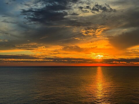 Sunset dramatic sky clouds over dark calm ocean