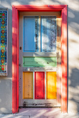 Fototapeta premium Colorful rustic wooden door with traditional tiles in the historic Kaleici district of Antalya, Turkey, featuring a vibrant red frame and distressed multi-colored panels on an old house facade