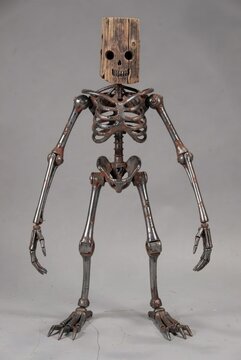 Rusty skeleton figure with wooden skull head standing upright against plain gray studio background