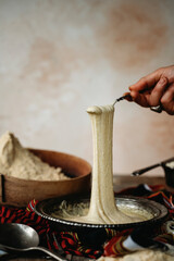 Obraz na płótnie Canvas Stretching hot gooey Turkish kuymak from a bowl