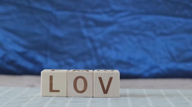 love, motivational word, laying out  by hand from letters on wooden cubes, slow motion
