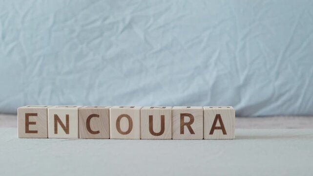 encourage, motivational word, laying out  by hand from letters on wooden cubes, slow motion
