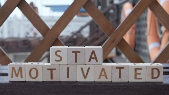 stay motivated, motivational phrase, laying out  by hand from letters on wooden cubes, slow motion

