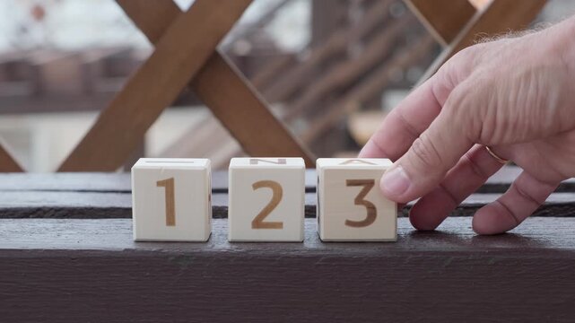 numbers 1 2 3, laying out  by hand from on wooden cubes, slow motion
