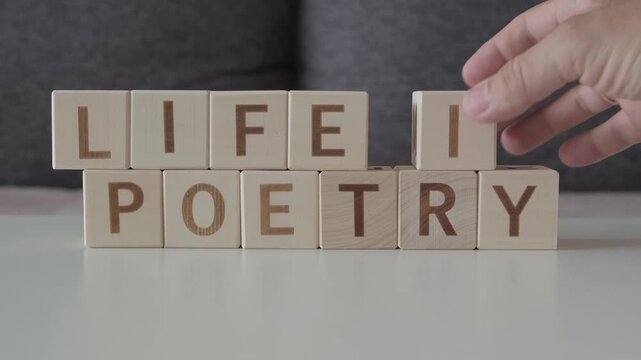 life is poetry, motivational phrase, laying out  by hand from letters on wooden cubes, slow motion
