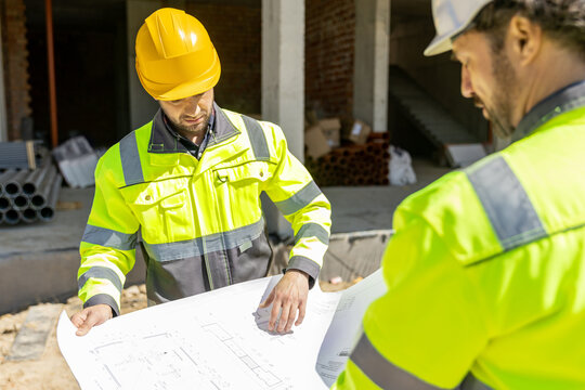 Professional builders analyzing blueprint architectural scheme