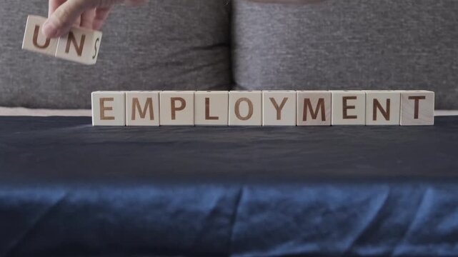 unemployment replacing with employment, motivational word, laying out  by hand from letters on wooden cubes, slow motion
