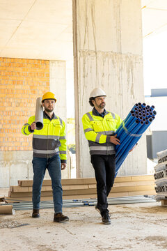 Two diverse construction workers carrying pipeline and pipe