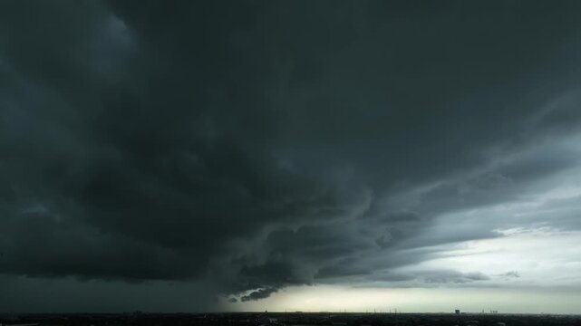 Aerial view of dramatic storm clouds covering the sky, showcasing dark rain-filled formations, powerful atmospheric movement, and an approaching thunderstorm over the distant landscape. 4k.
