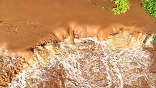 Aerial close up of fast flowing floodwater during an extreme weather event, showing chaotic water movement, disaster risks, and the consequences of climate change on natural ecosystems. 4k.

