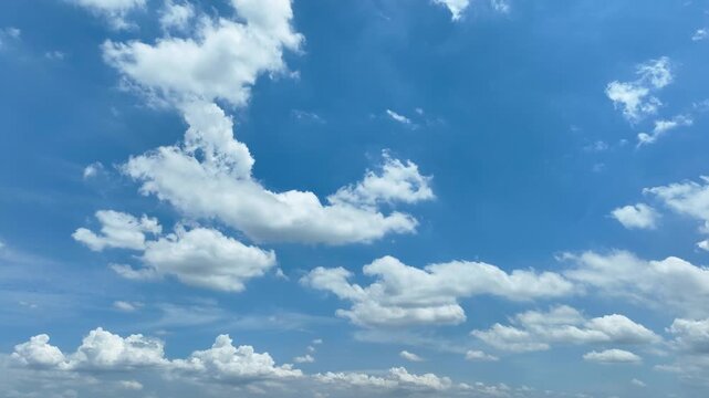 Drone perspective capturing a vibrant blue sky with scattered fluffy clouds, highlighting the beauty of nature, calm atmospheric conditions, and the endless expanse of the daytime sky. 4k.

