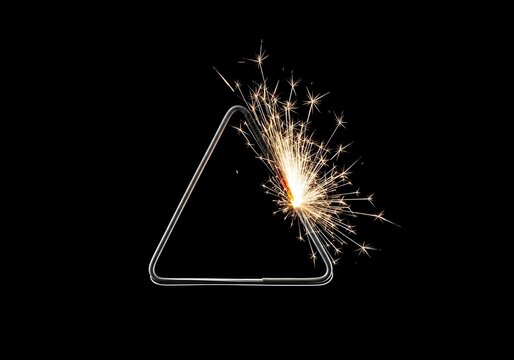 Glowing sparks on a metal triangle frame against black