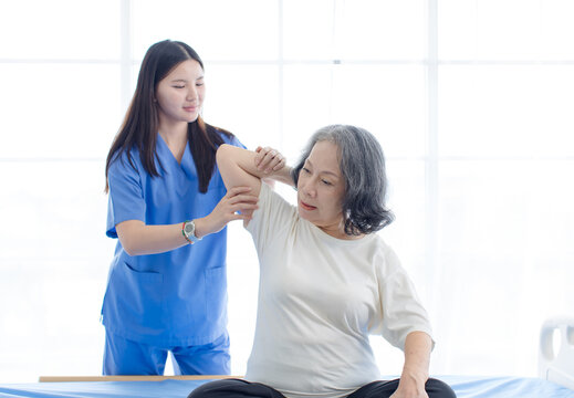 Asian female doctor physical therapist help senior woman back rehabilitation posture therapy in healthcare clinic professional patient care elderly recovery support wellness quality medical services.