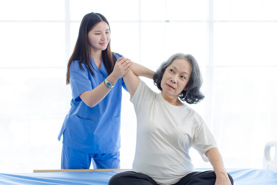 Asian female doctor physical therapist help senior woman back rehabilitation posture therapy in healthcare clinic professional patient care elderly recovery support wellness quality medical services.