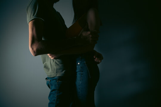 Young couple in love holding hands on dark background, close-up