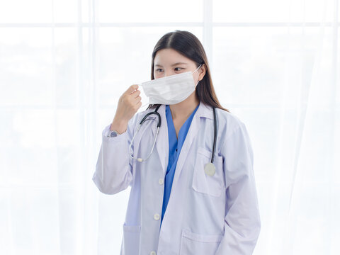 Asian woman doctor wearing protection face mask white medical coat in hospital clinic representing medical care infection flu disease prevention professional healthcare patient safety hygiene wellness
