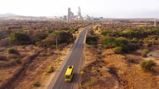 Drone footage of a cement manufacturing plant in Kajiado County, Kenya, with a highway, bus and surrounding semi-arid landscape, showcasing industrial growth, infrastructure and regional dev