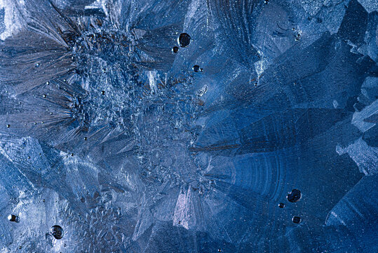 Close up view of frosty ice patterns and blue crystal textures on glass