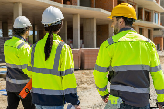 Close up of three builders in helmets looking at structure