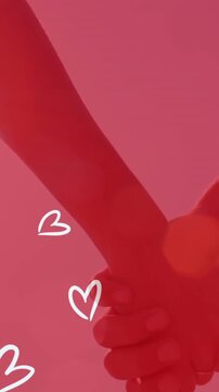 Animation of white hearts over caucasian couple holding hands