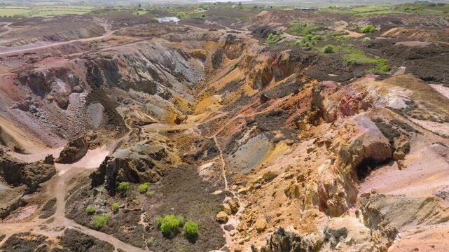 Parys Mountain Copper Mine, Amlwych, Anglesey, Wales, UK. Flight over main excavation site showing mineral colours and paths at crater base.
