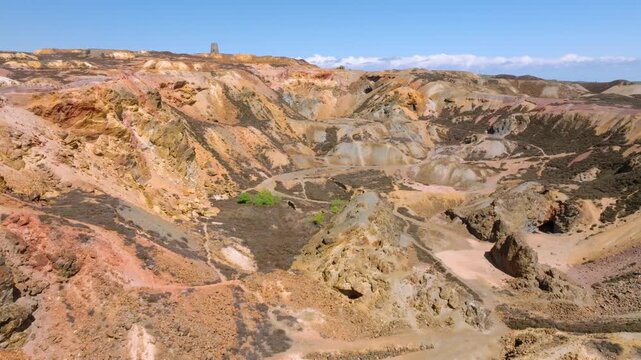 Parys Mountain Copper Mine, Amlwych, Anglesey, Wales, UK. Drone rise over main crater showing mineral colours with green hills becoming visible.