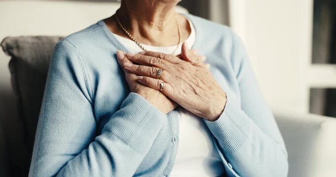 Elderly, woman and hands in retirement home with chest pain, heartburn symptoms and health problem. Uncomfortable, senior person and acid reflux in living room with indigestion, illness and disease.