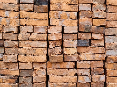 Traditional red clay bricks piled up on a construction site, industrial material background.
