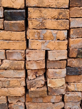Traditional red clay bricks piled up on a construction site, industrial material background.