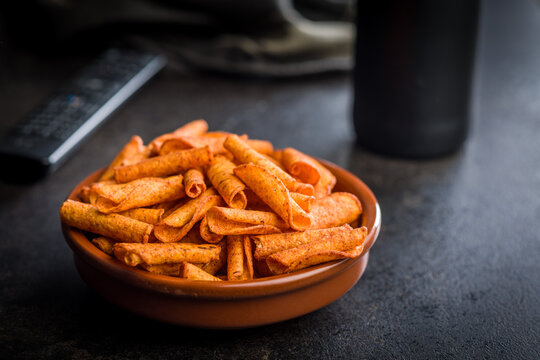Spicy Rolled Corn Snacks in Bowl With Seasoning . Crunchy Orange Party Snack Closeup