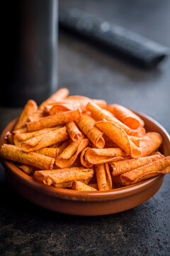 Spicy Rolled Corn Snacks in Bowl With Seasoning . Crunchy Orange Party Snack Closeup