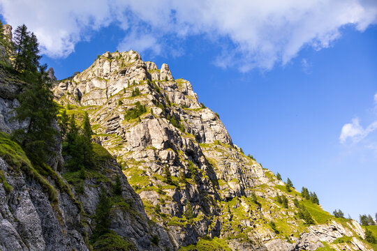 Sunlit Massive Rocky Cliff Face under Blue Sky in Bucegi Mountains